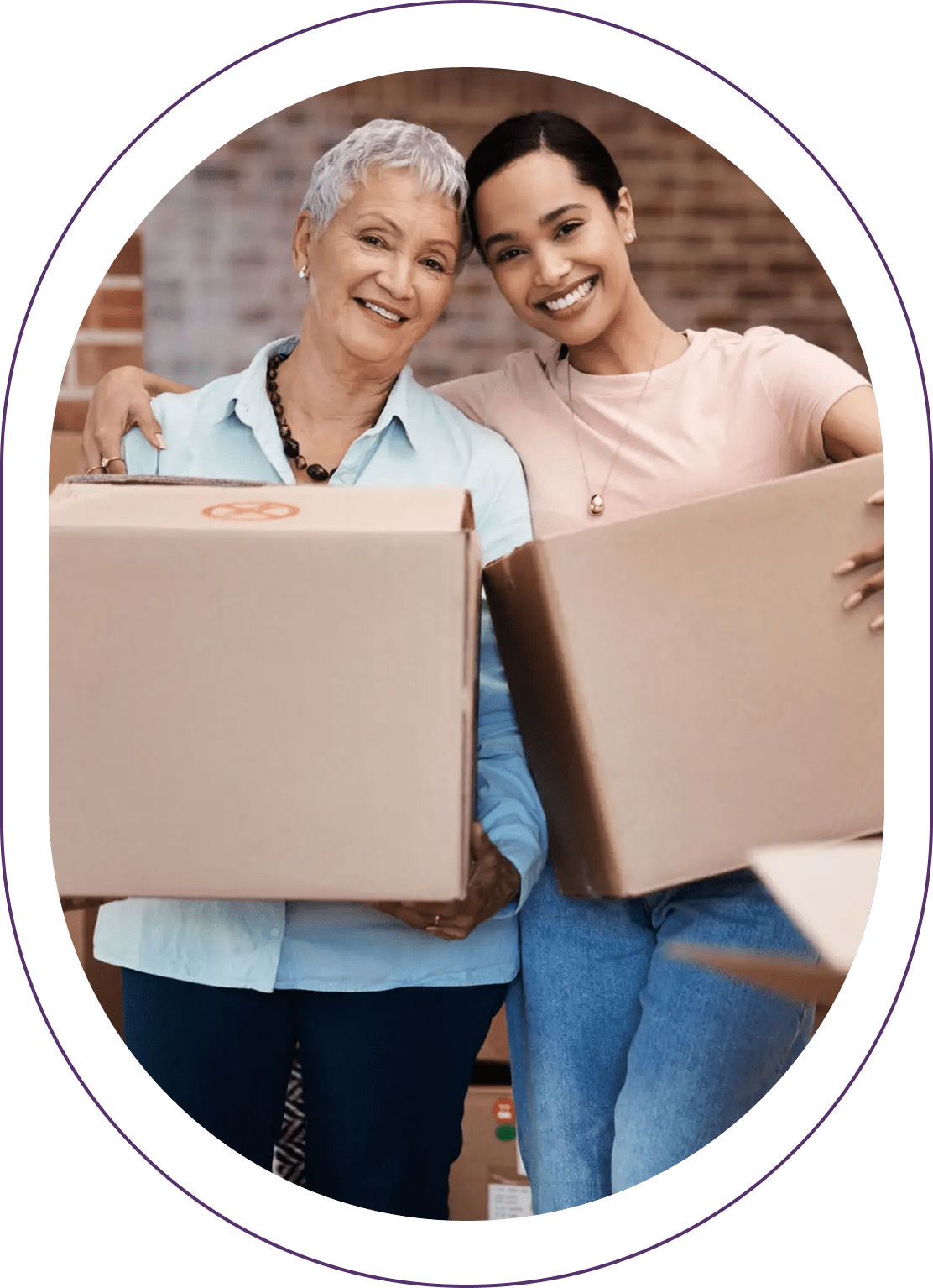 Two women smiling, holding cardboard boxes.