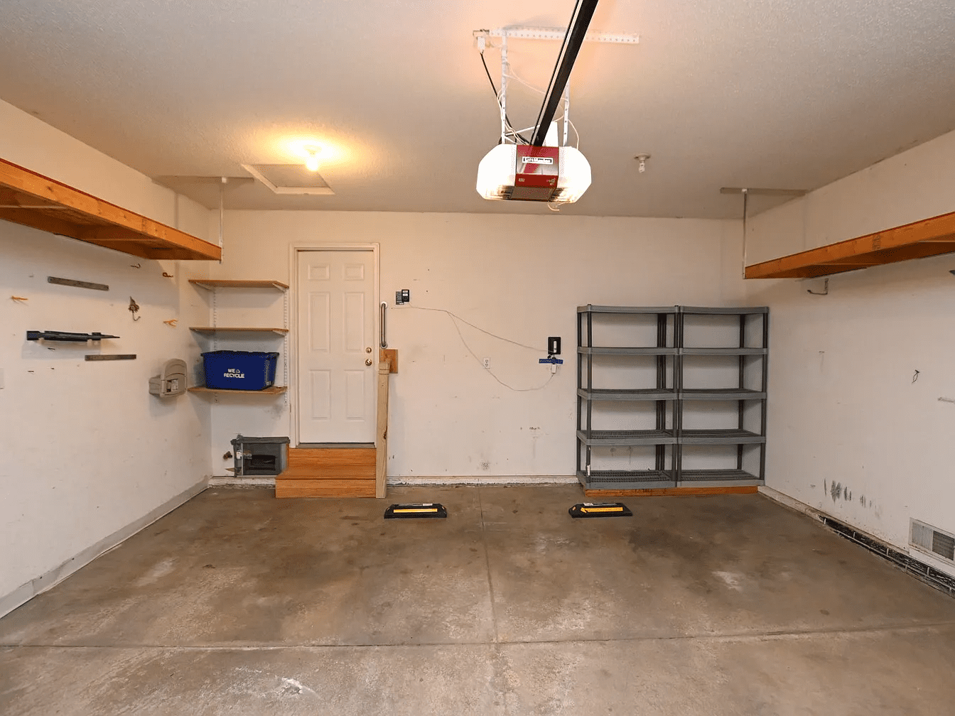 Empty garage with shelving and overhead lighting.