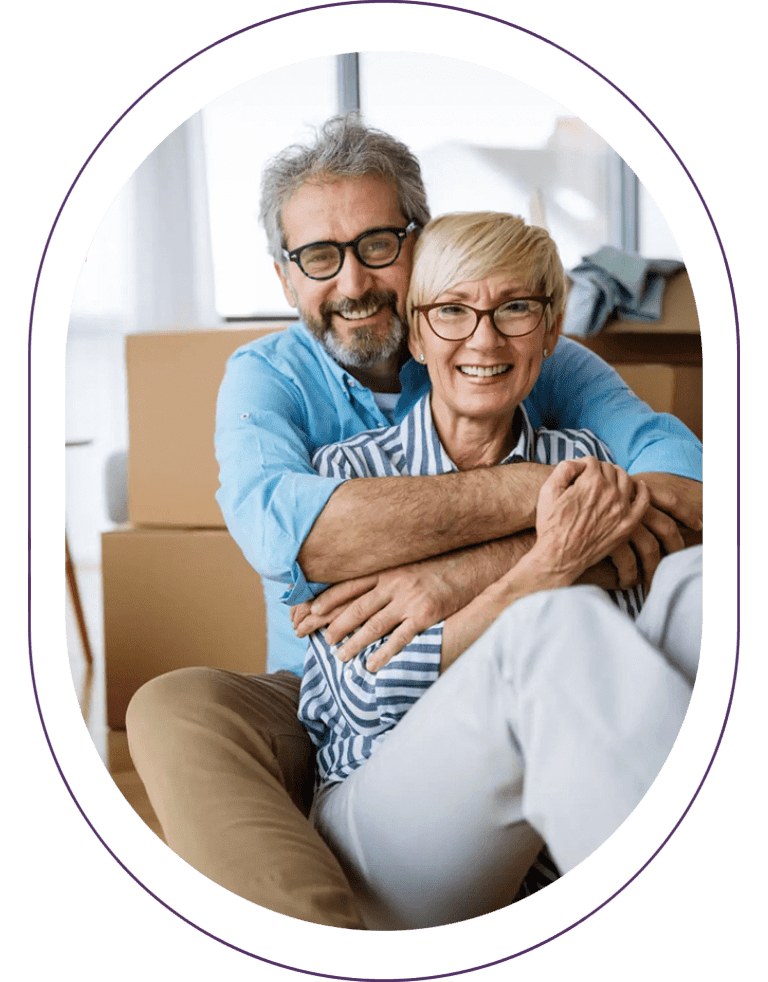 Smiling couple embracing with moving boxes.