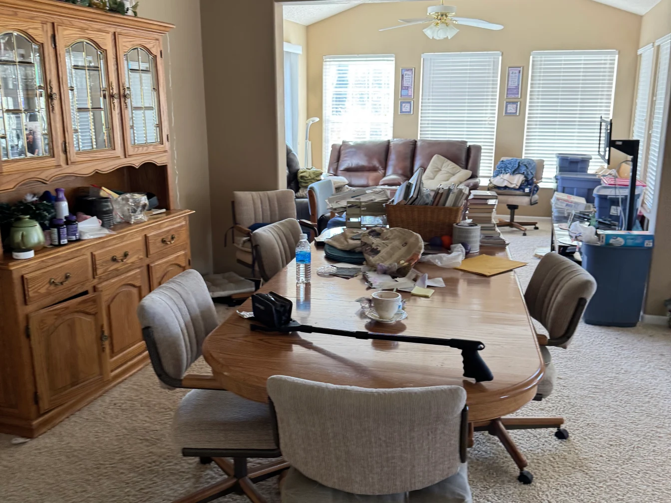 Dining room with cluttered table and chairs.