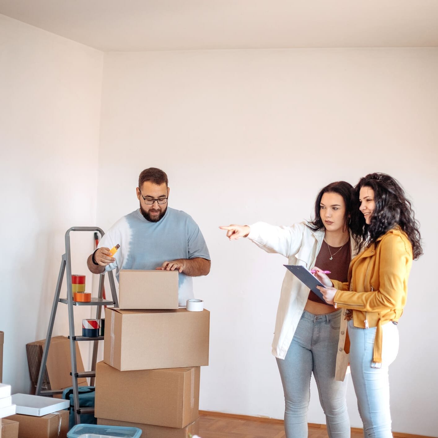 People organizing boxes in an empty room.